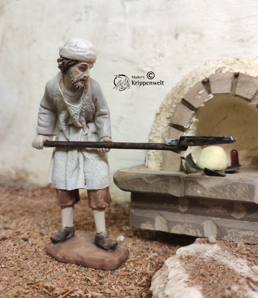 eine Bäcker mit Brotschieber beim Beladen eines Ofens