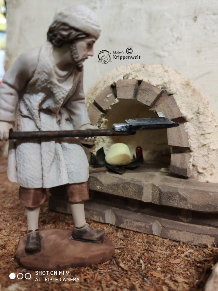 eine Bäcker mit Brotschieber beim Beladen eines Ofens